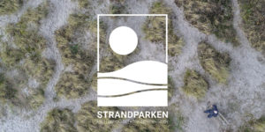 Dronefoto af klitter med Strandparkens logo